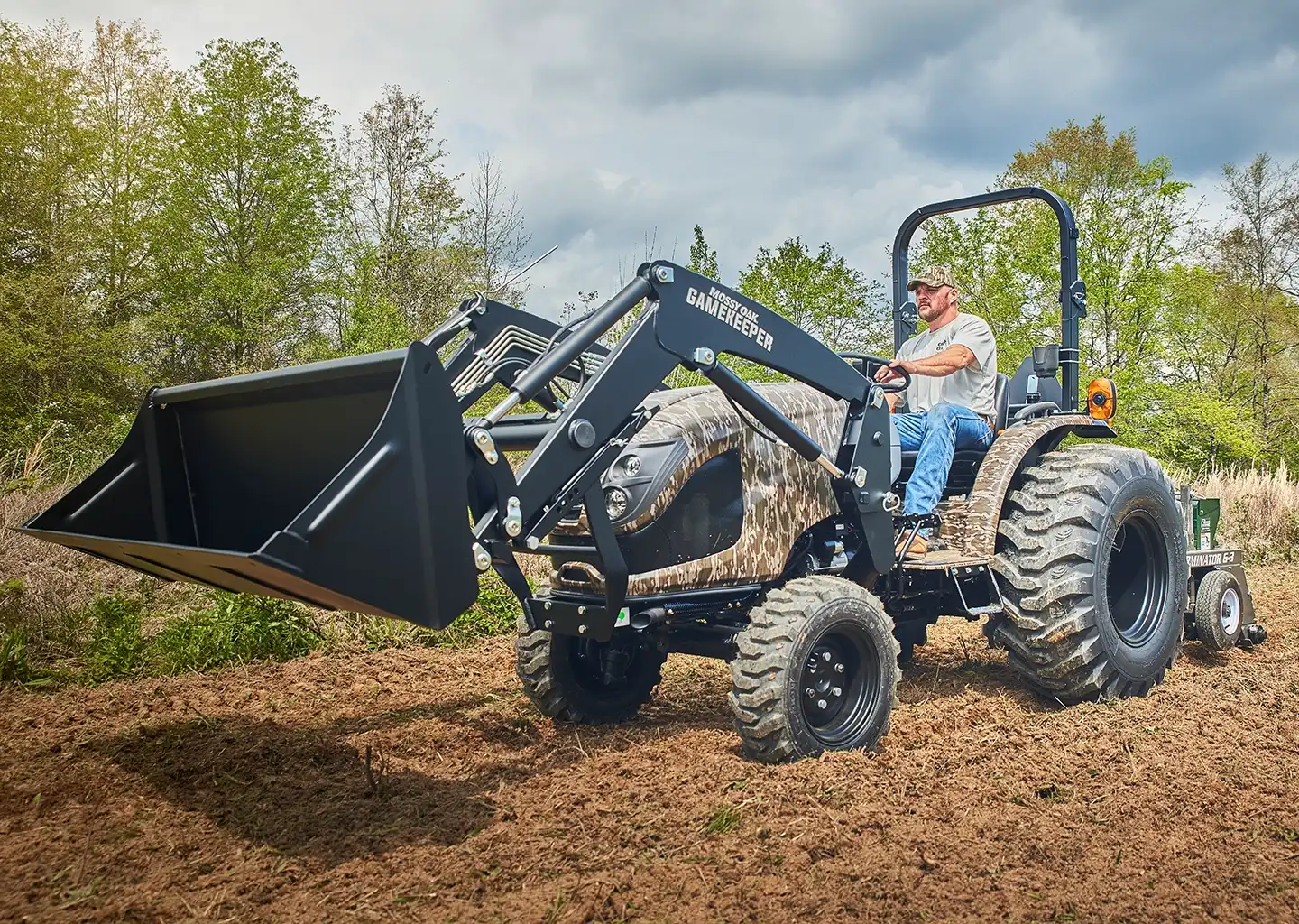 a man sits on an ls tractor that reads mossy oak gamekeepr