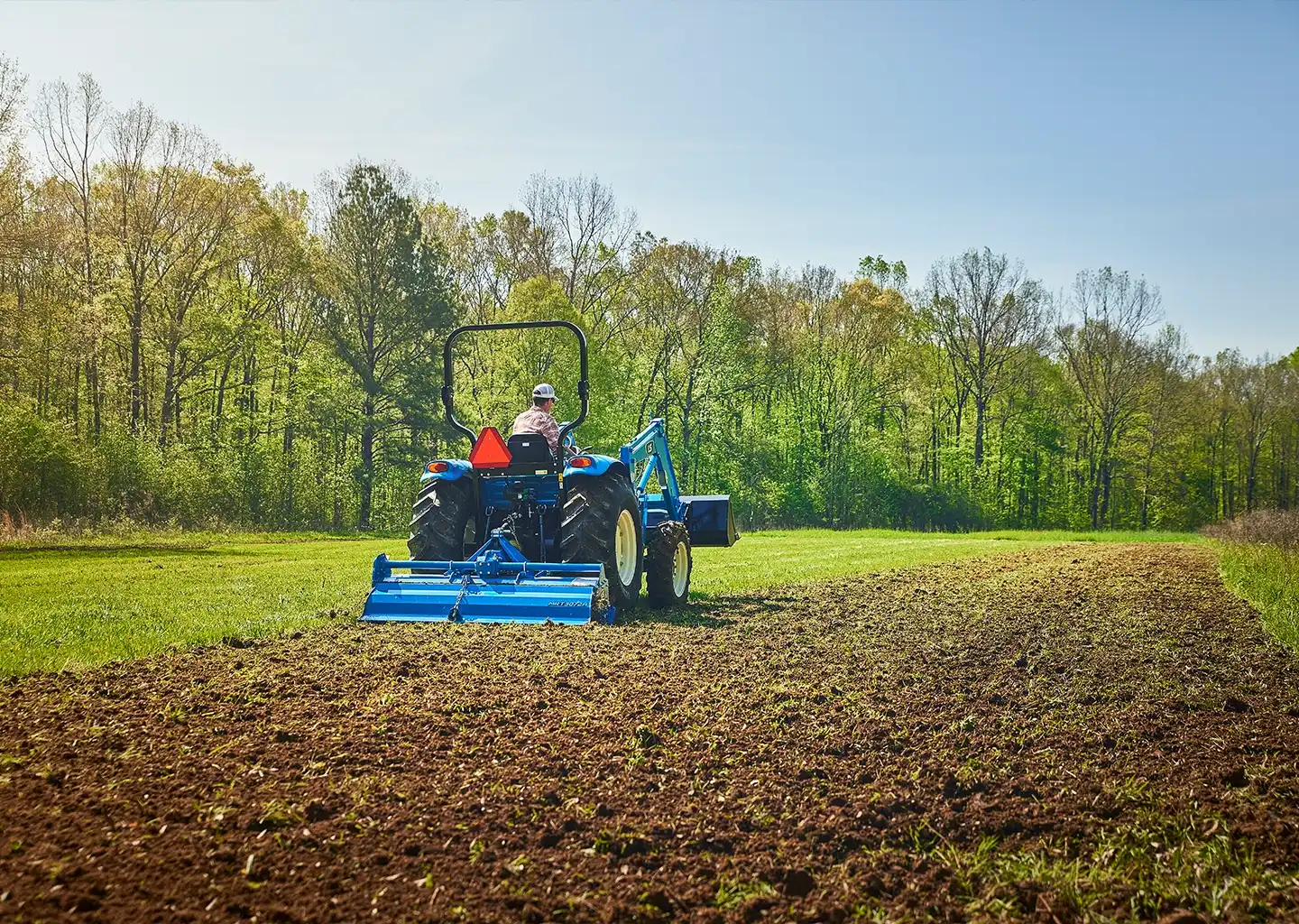 a man on a tractor tills a field