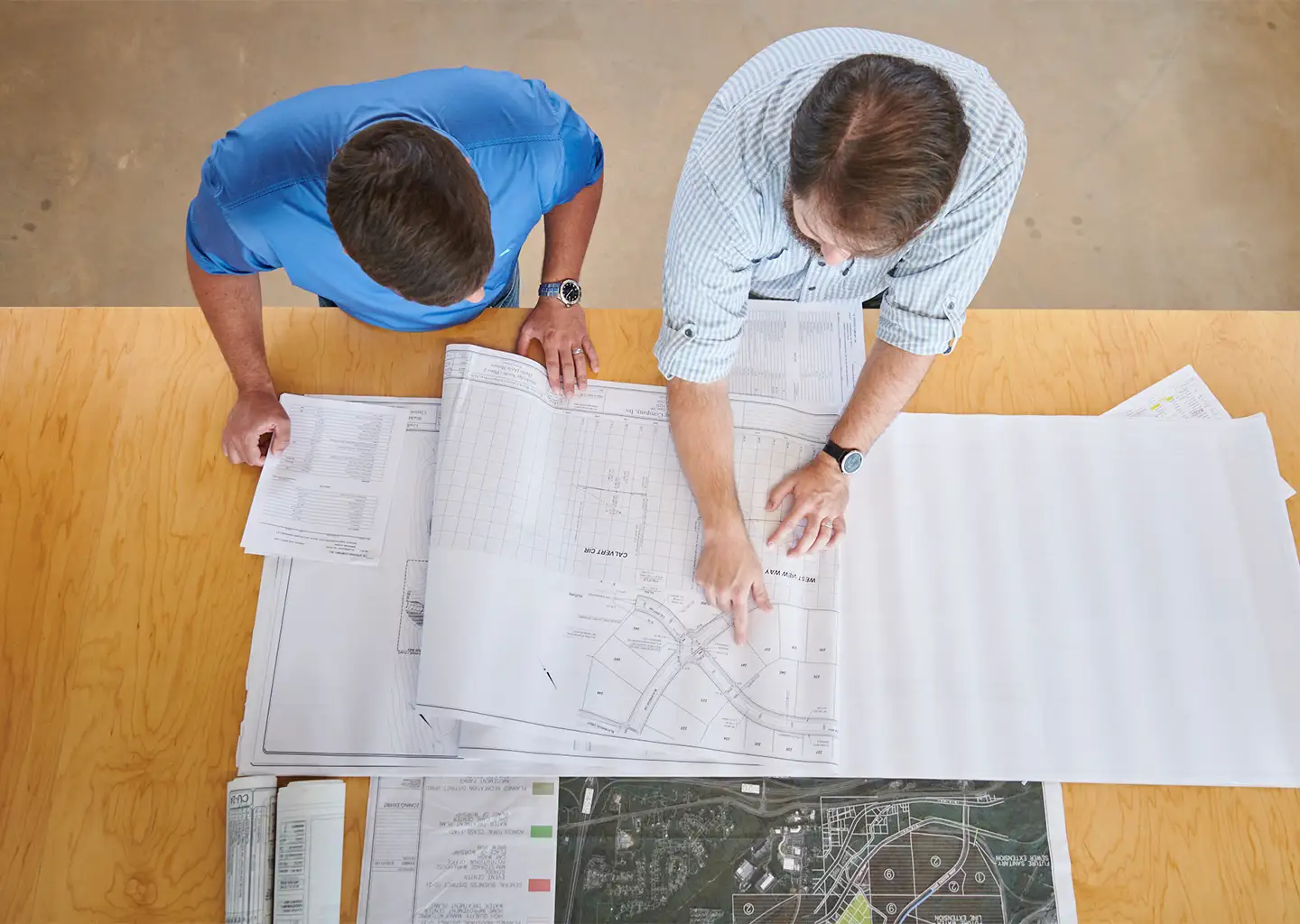 2 architects pointing at plans on a desk