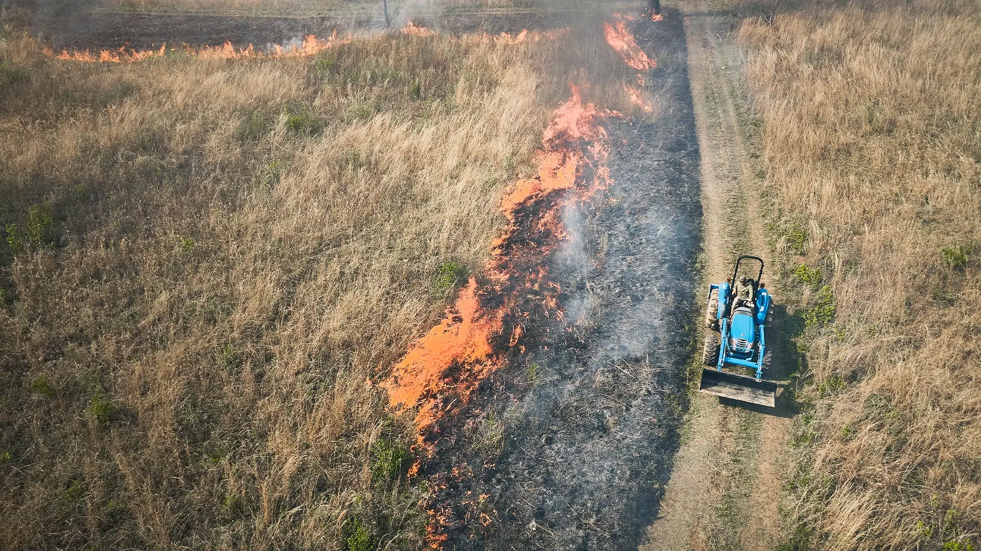 a tractor in a field that is being burned